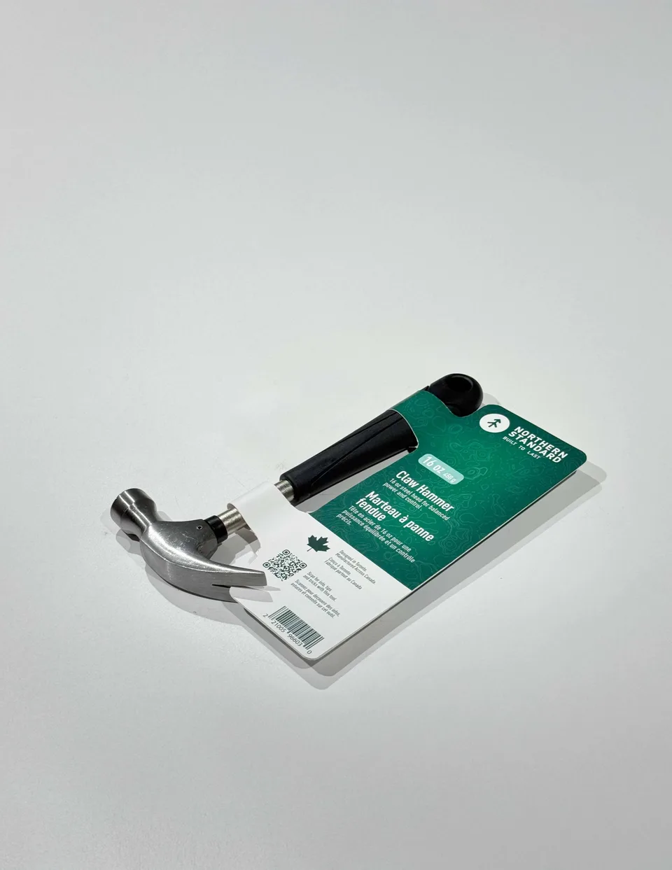 Northern Standard claw hammer prototype on an off-white studio surface, with green bilingual packaging card attached